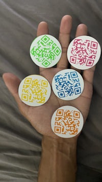 four qr code stickers in a person's hand